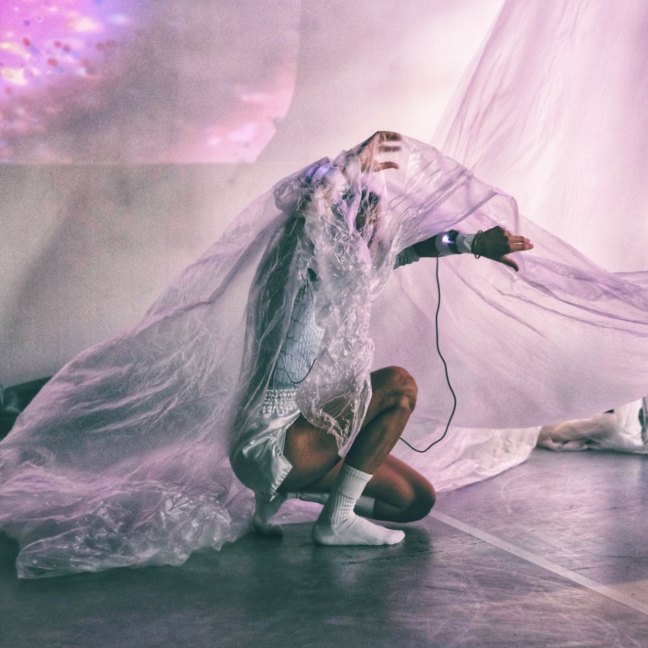 The dancer Victoria Henneberg, squatting, under a thin and transparent foil.